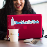 Young woman working remotely with a laptop in a modern indoor office setting, showcasing tech culture.