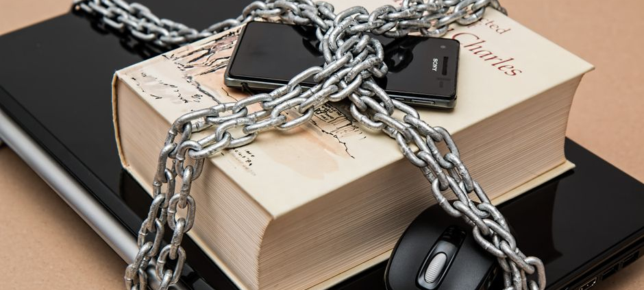 Chain-locked book, phone, and laptop symbolizing digital and intellectual security.