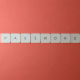 Focus on password security with white keyboard tiles spelling 'PASSWORD' on a coral background.